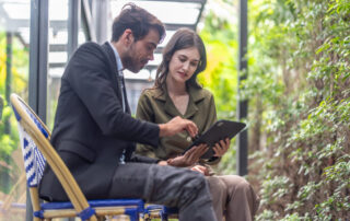 2 business people looking at ipad sitting in an atrium